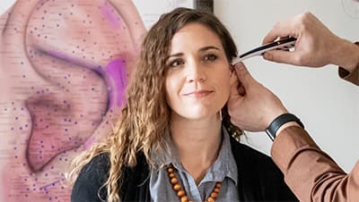 A practitioner treating an ear point during an auriculotherapy session.