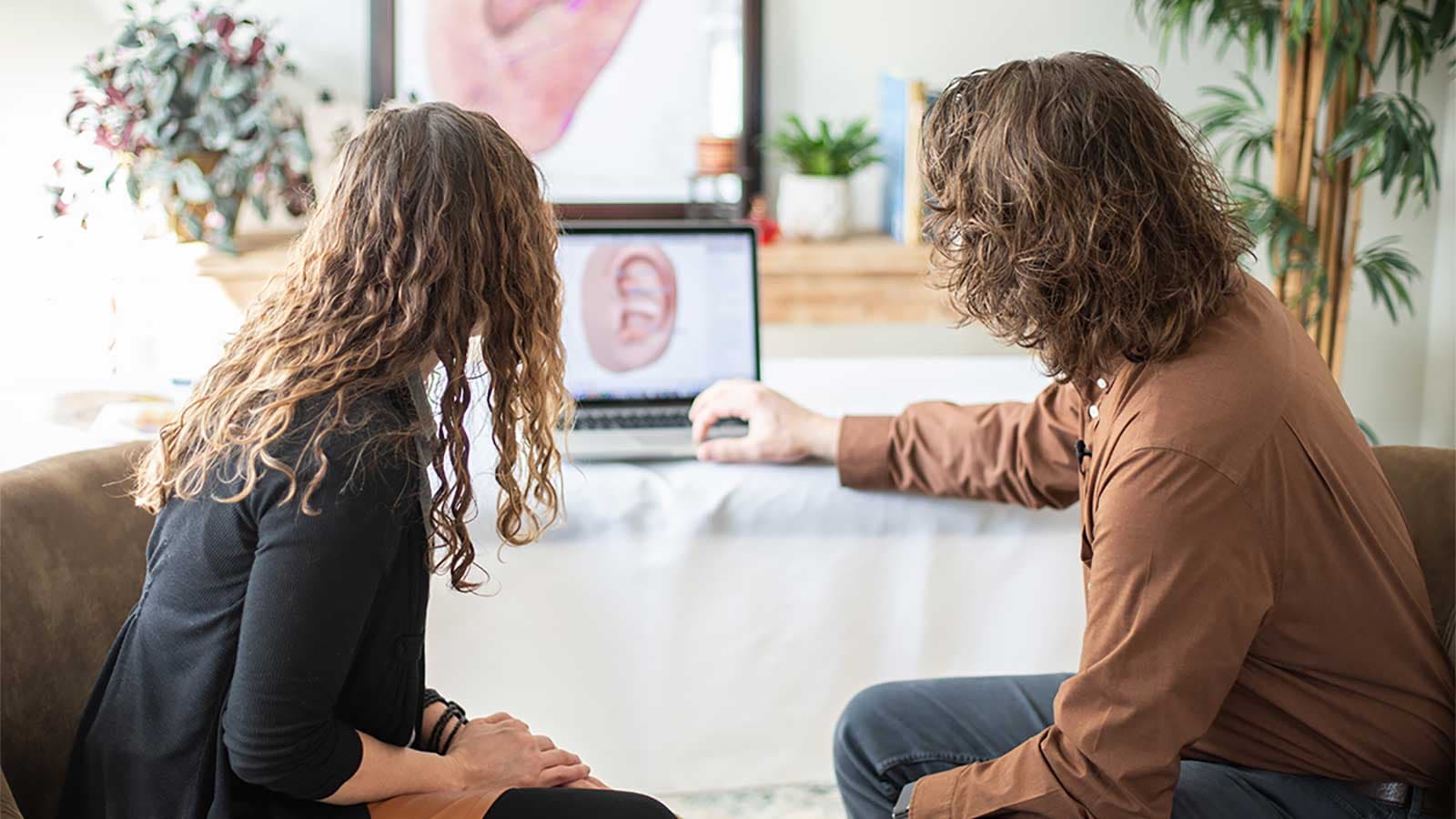 A practitioner showing Auriculo 360 on a laptop during a treatment.