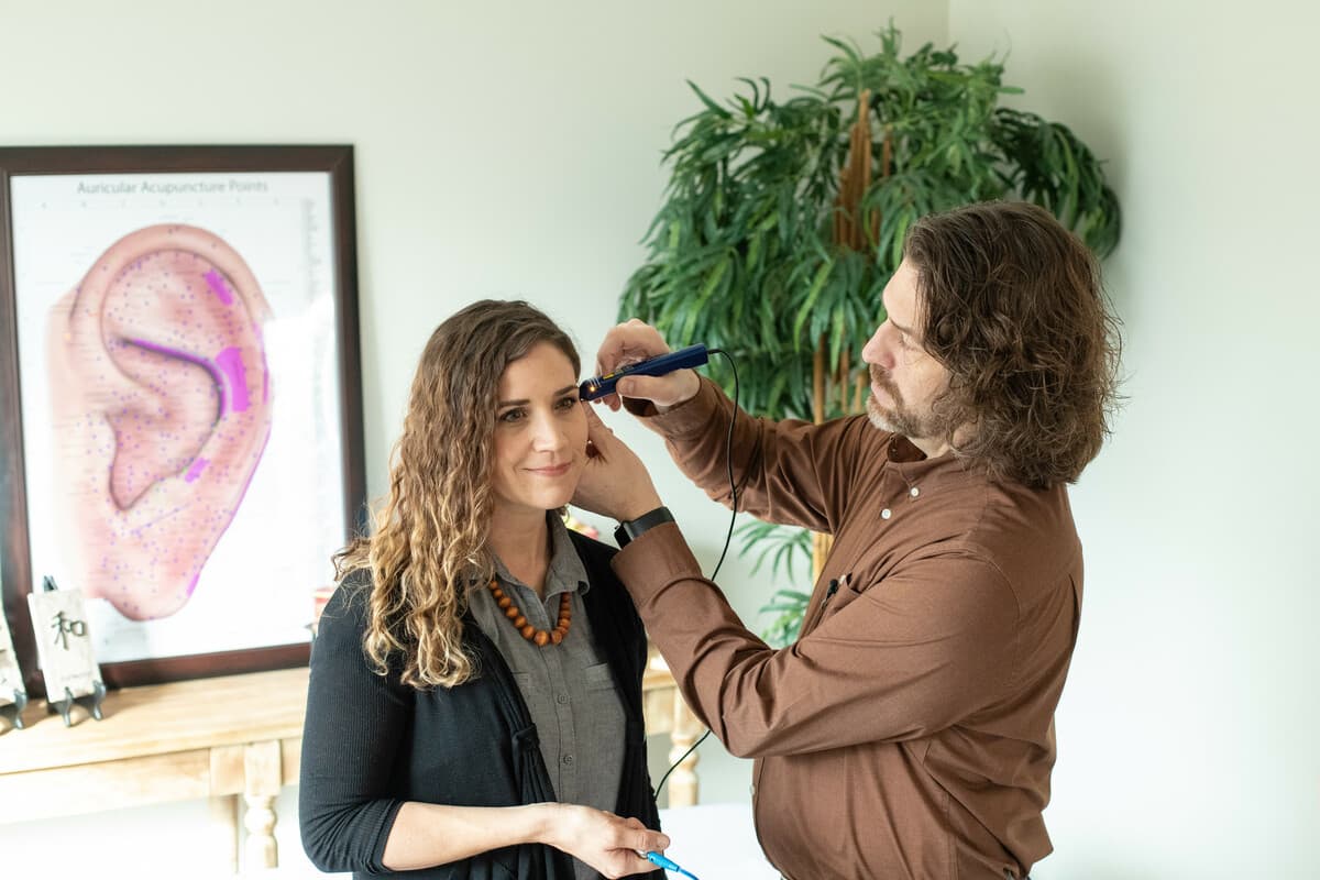 A practitioner treating a patient's ear during auriculotherapy.